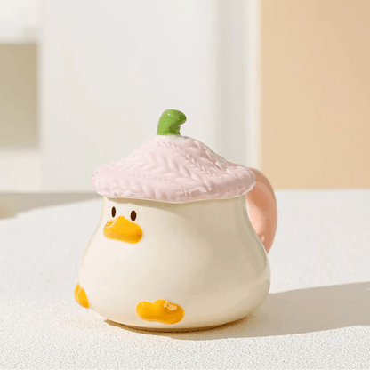 Duck-shaped ceramic mug with pink textured lid, orange beak face, and side handle