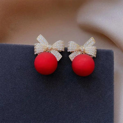 Gold-tone bow stud earrings with red ball ornaments and rhinestone sparkle