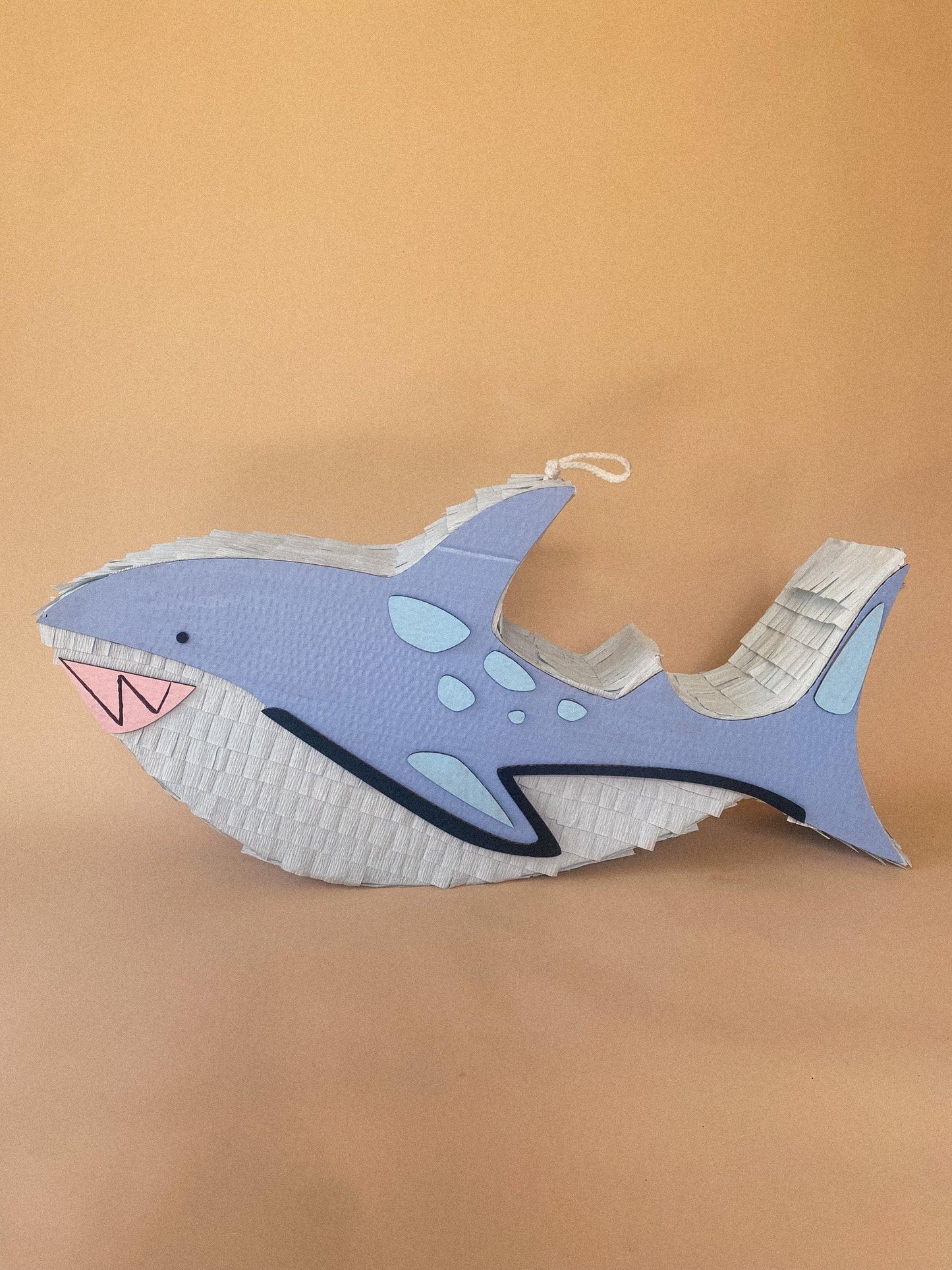 Handmade shark-shaped piñata in light blue with white fins and hanging loop