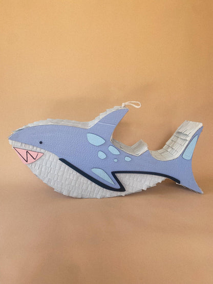 Handmade shark-shaped piñata in light blue with white fins and hanging loop