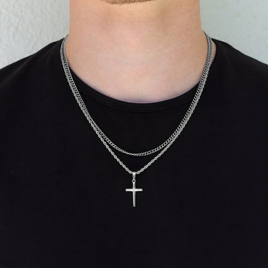 Silver cross necklace set with double chain and small cross pendant centered on chest