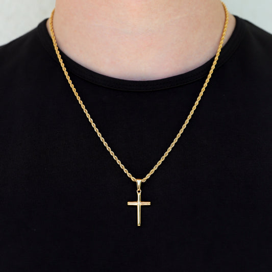 Gold-tone cross pendant necklace worn at neck, small dangling cross on chain