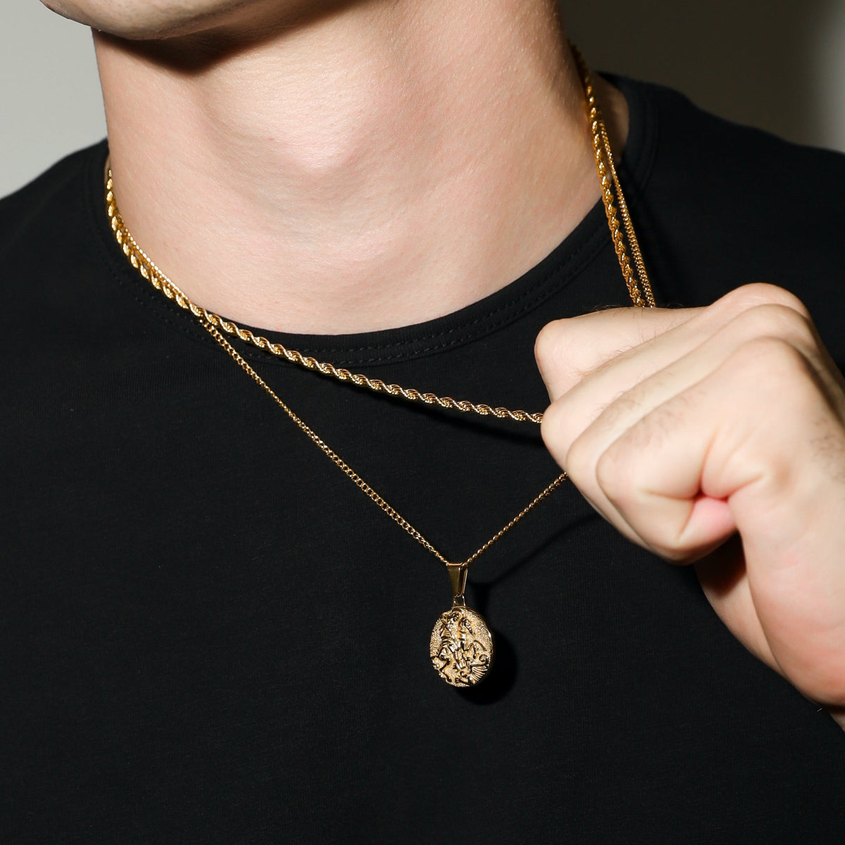 Gold coin pendant necklace with hand adjusting the chain near the collar