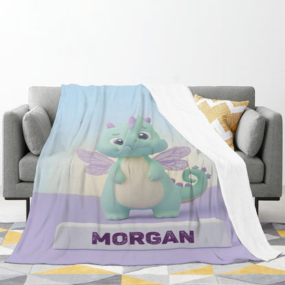 Printed blanket laid on sofa; light blue dragon design with purple bottom band and “MORGAN”