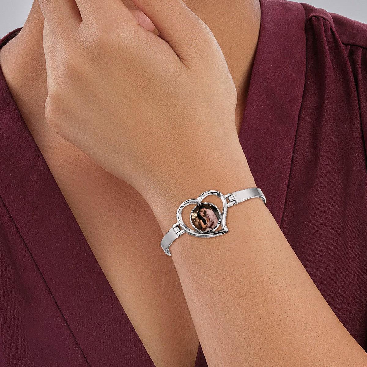 Heart photo bracelet worn on wrist with light-colored strap and round picture window