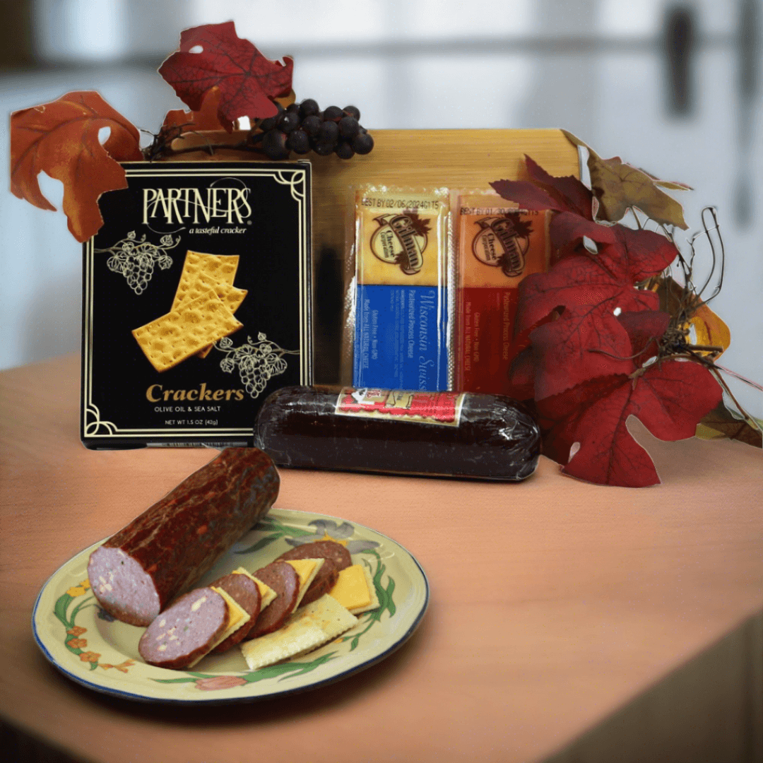 Gourmet board gift set with crackers, sausage, and cured meats on a wooden board