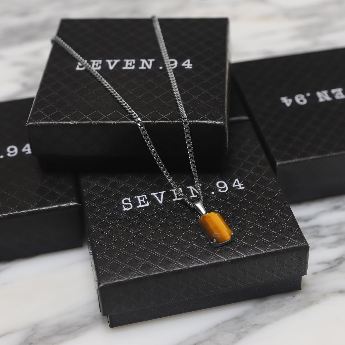 Silver tiger eye stone pendant on chain with black gift boxes in view