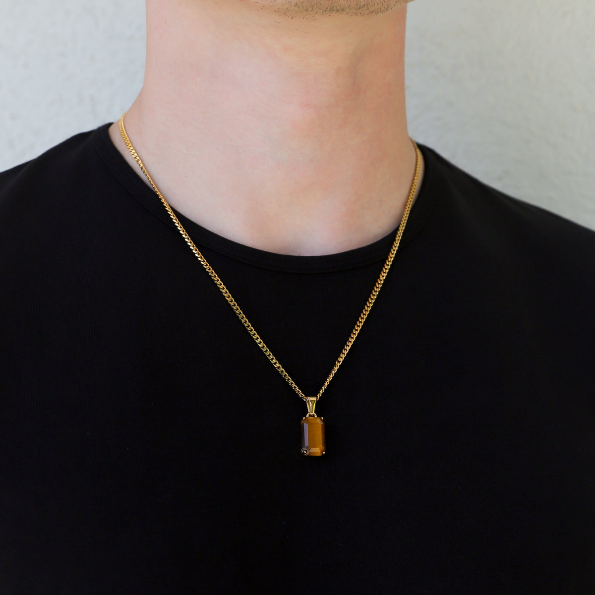 Gold tiger eye pendant on linked chain centered on the chest over a black shirt