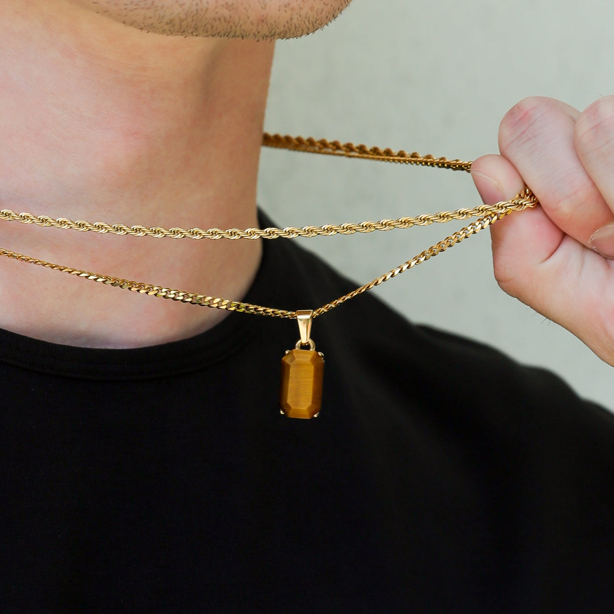 Close-up of gold tiger eye pendant necklace set with layered chains and rectangular charm