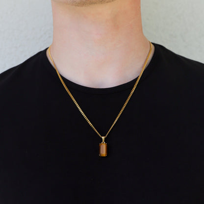 Gold tiger eye stone pendant necklace on a linked chain, worn on a man in black