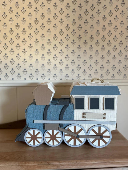 Piñata de tren artesanal con vagones azules, ventanas negras y ruedas blancas decorativas