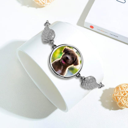 Silver bracelet with round photo locket and detailed angel wing charms, lobster clasp