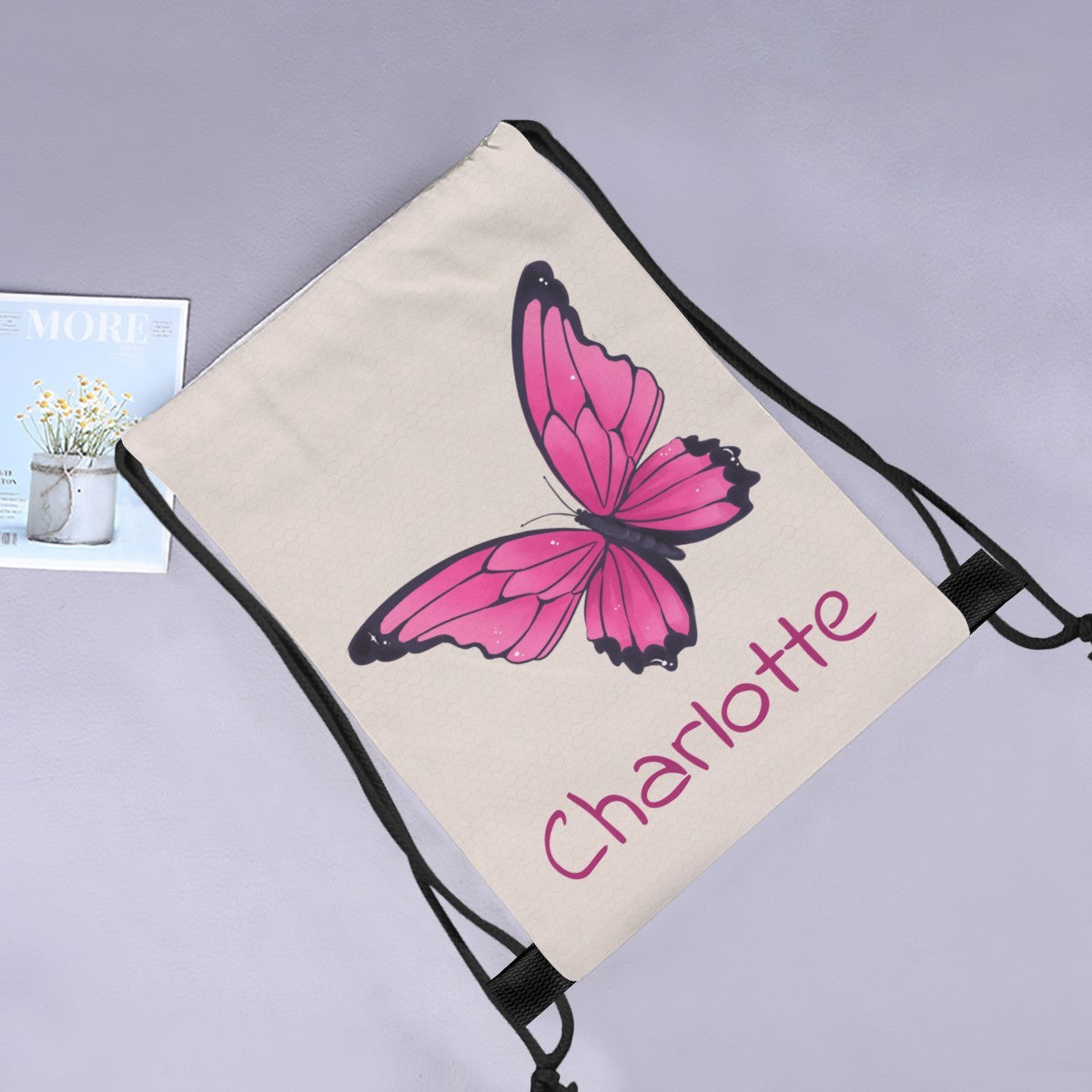 Butterfly drawstring bag with pink butterfly print and 'Charlotte' on cream fabric.