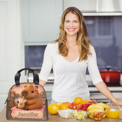 Kids lunch bag on table, brown bear-and-flower front with Jennifier logo, held by woman.