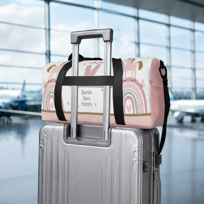 Unicorn duffel bag with black strap attached to wheeled suitcase handle