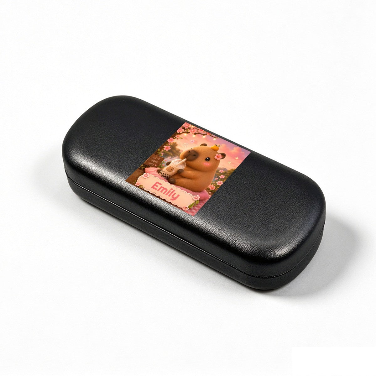 Black hard eyeglasses case with capybara photo insert, angled view.