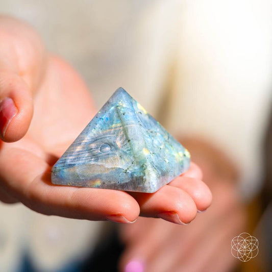 Indian labradorite pyramid crystal with carved eye design, held in a hand