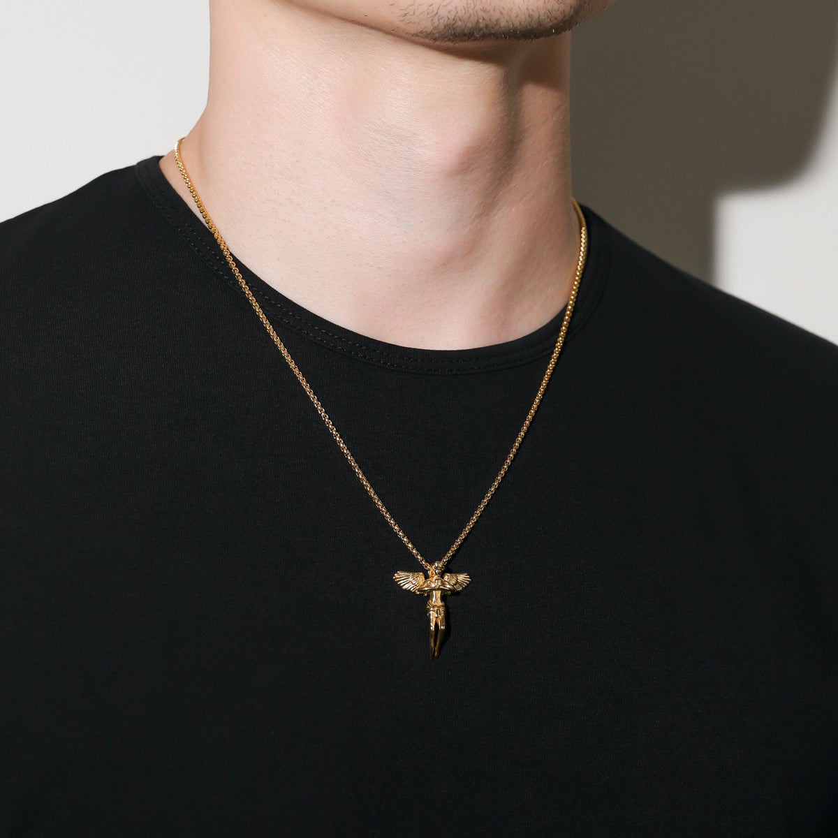 Gold rope chain necklace with guardian angel pendant, angled view on neck