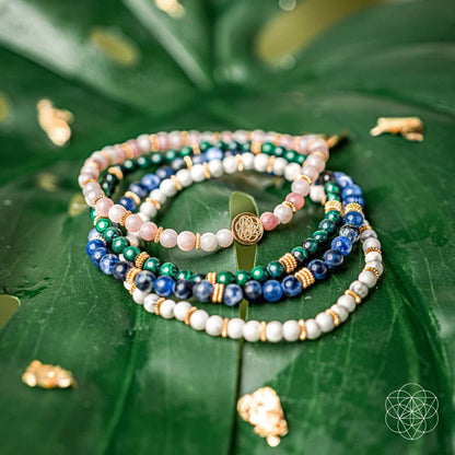 Stack of beaded bracelets with blue, green, white, and pink beads and gold charm