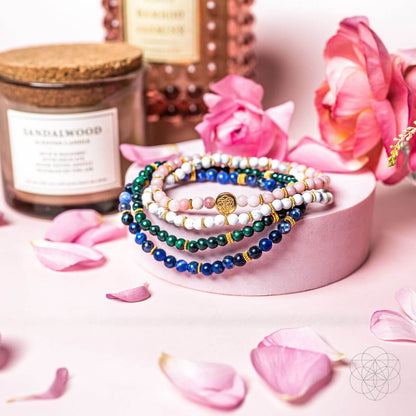 Beaded bracelets on pink display with blue, green, white stones and gold charm