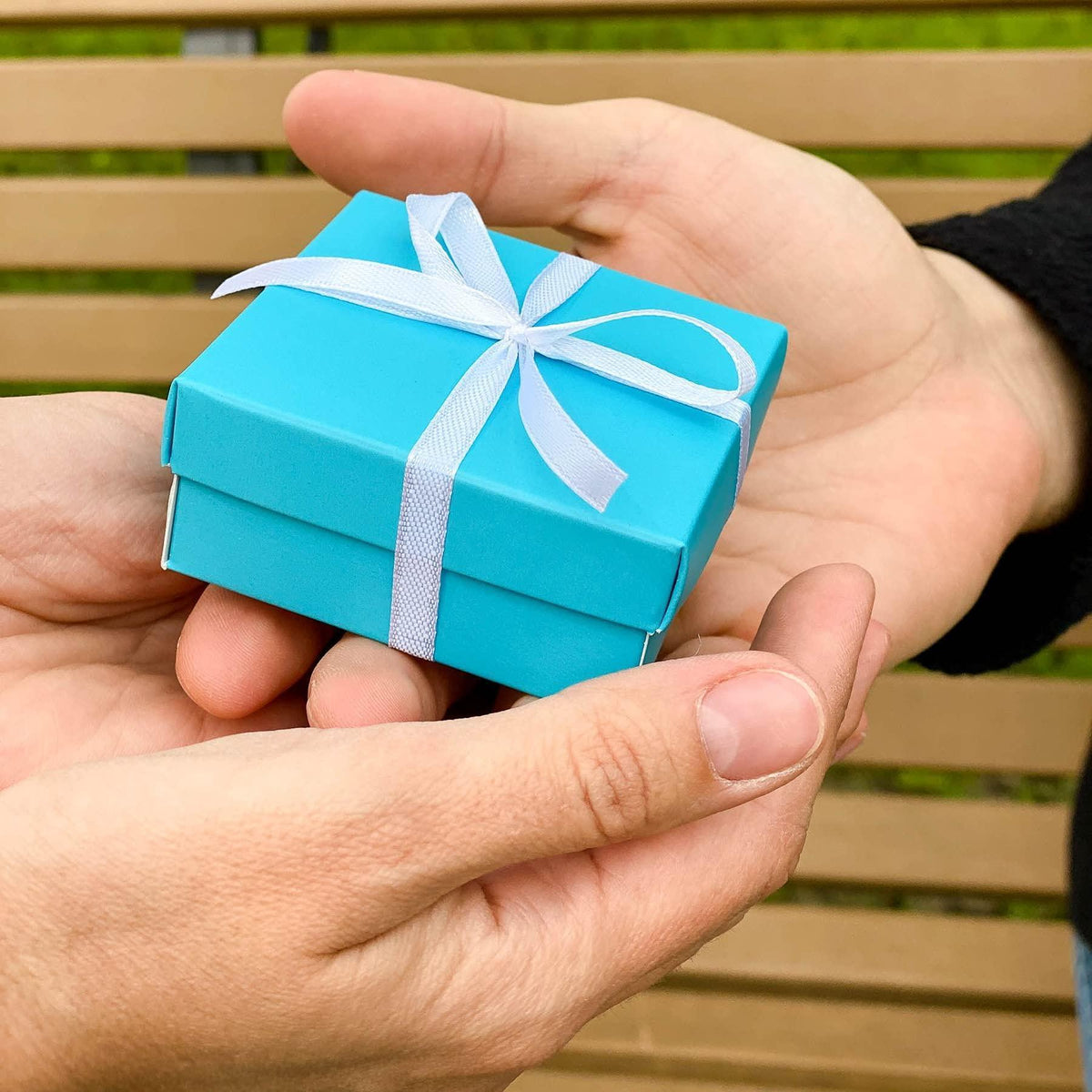 Turquoise gift box with white ribbon bow held in hands
