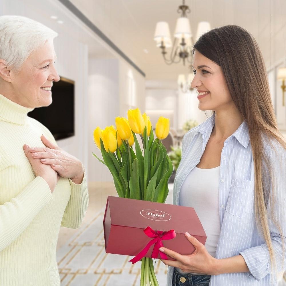 Red gift box with ribbon and tulip bouquet, handed to a recipient