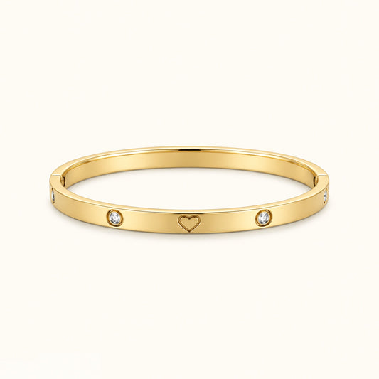 Gold-tone bangle bracelet with heart motif and two round clear stones