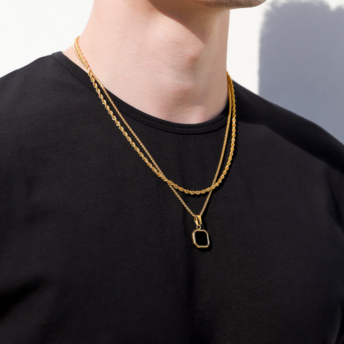 Gold-tone double-strand chain necklace with black octagon pendant at neckline