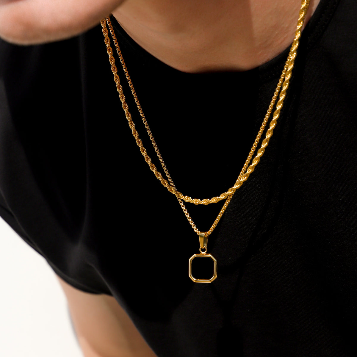 Close-up of gold-tone chain with black octagon onyx pendant bezel