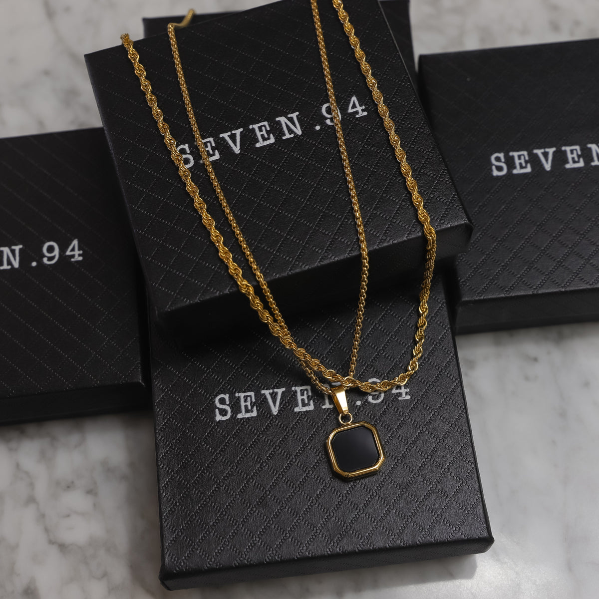 Gold pendant set with two square black onyx pendants on black gift boxes