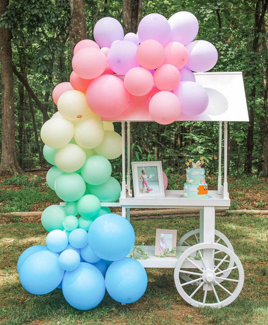 Pastel balloon garland arch with clustered balloons in blue, pink, and green