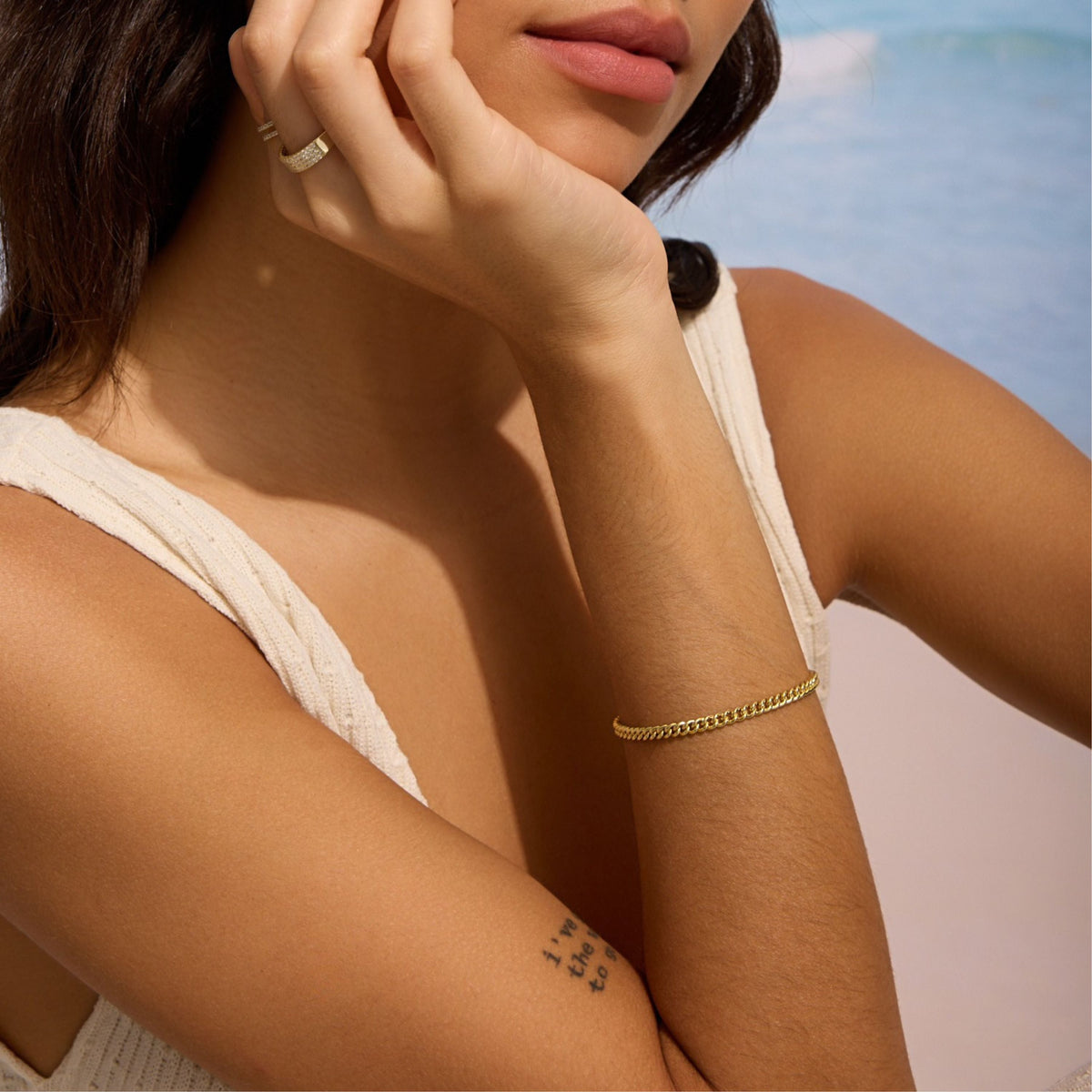 Gold curb chain bracelet on forearm with smooth link shine