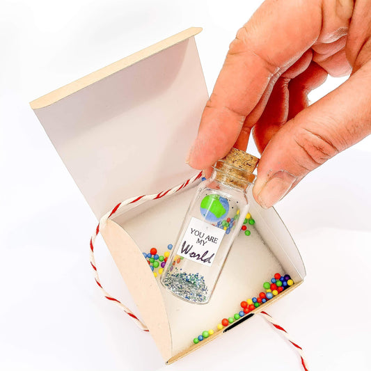 Mini bottle message in craft gift box with ribbon, opened to show the globe inside