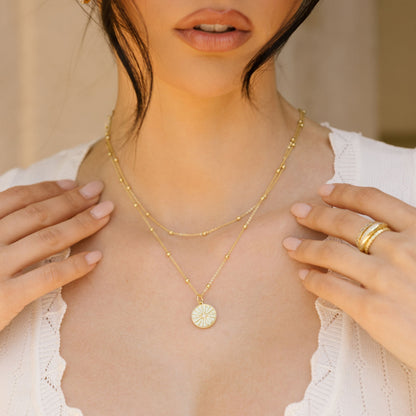 Gold compass pendant necklace with round compass medallion on a delicate chain