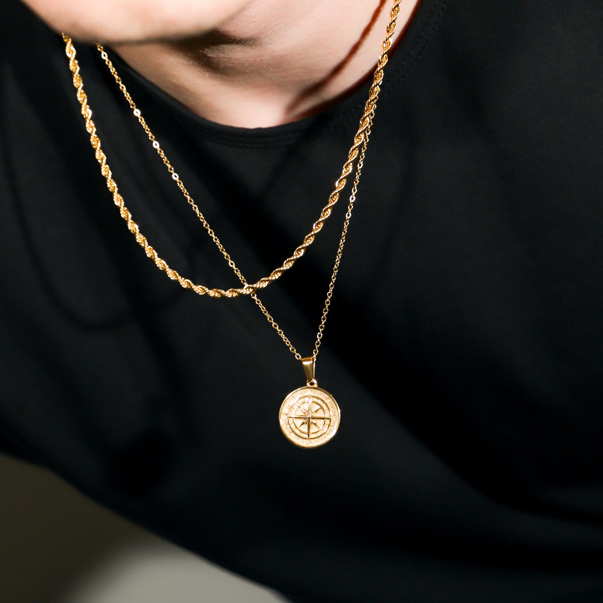 Gold compass pendant with rope chains, layered necklace close-up