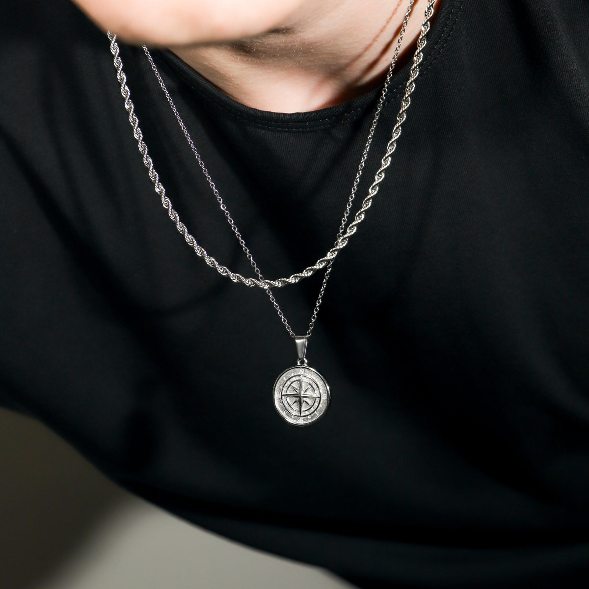 Silver compass pendant with rope chains, layered necklace close-up