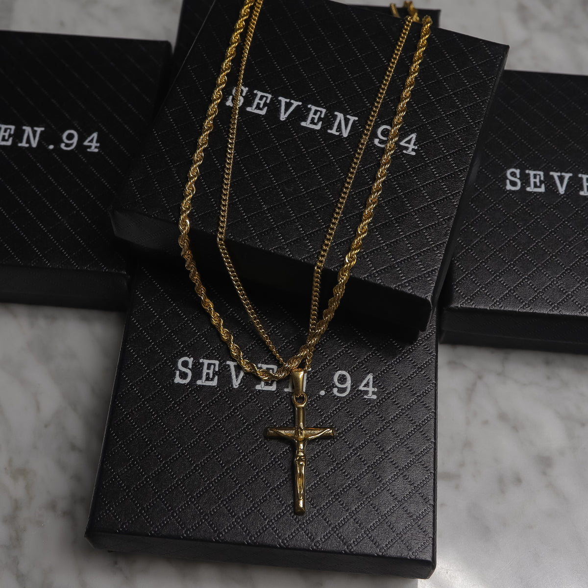 Gold crucifix pendant necklace set on black gift bags