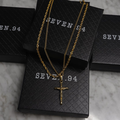 Gold crucifix pendant necklace set on black gift bags