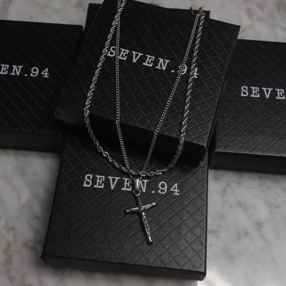 Silver crucifix pendant necklace set on black gift bags
