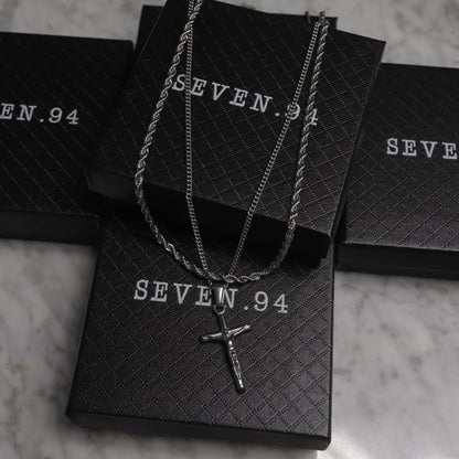 Silver crucifix pendant necklace set on black gift bags
