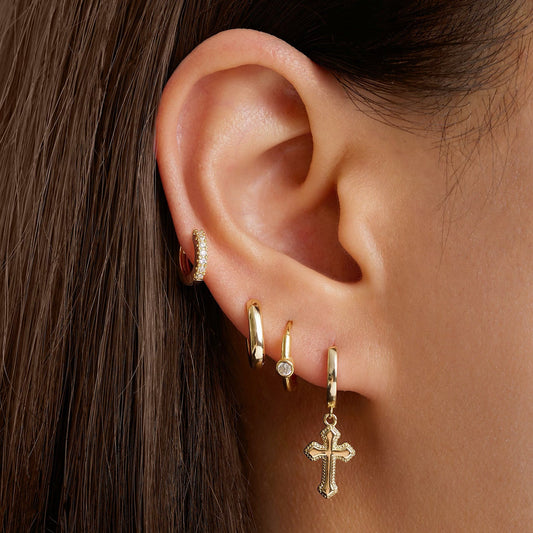 Gold cross hoop earrings on ear, small hinged hoops with dangling cross