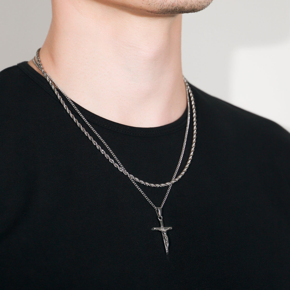 Silver crucifix cross pendant necklace with layered rope chains, on model neck