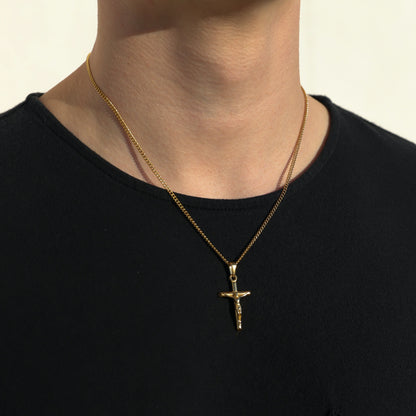 Gold crucifix pendant necklace on curb chain, worn on chest against black shirt