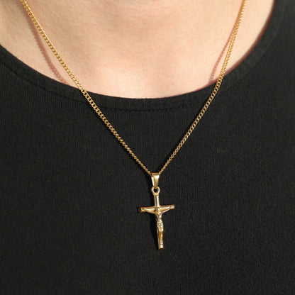 Gold crucifix pendant on curb chain with circular bail, close-up on black shirt