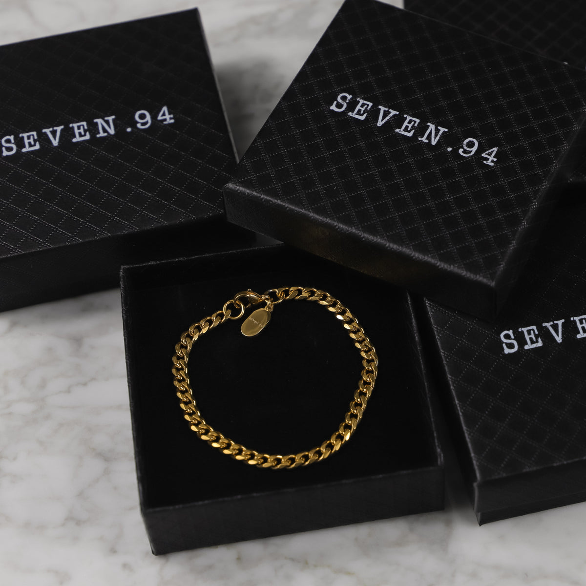 Gold Cuban link bracelet in black gift box, SEVEN.94 branding on packaging