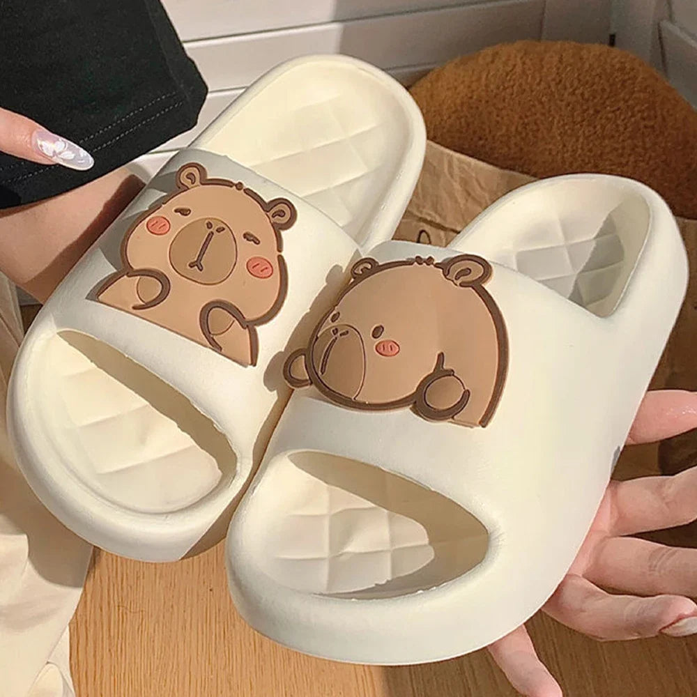 White capybara slide sandals with brown cartoon face on wide strap.
