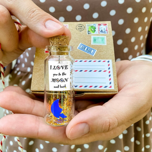 Small corked keepsake bottle with moon label, held in hands beside gift box