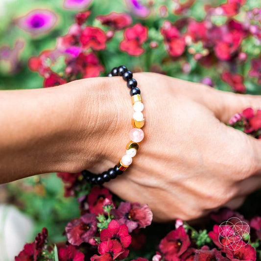 Hand wearing black beaded bracelet with pink and white gemstone beads
