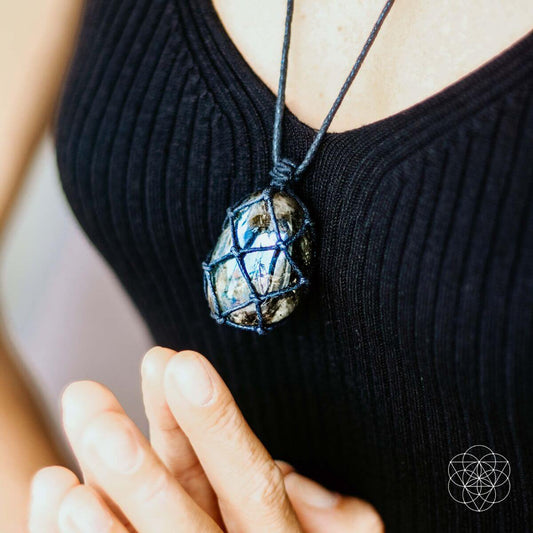 Blue iridescent transformation pendant on a black cord, worn at the neckline