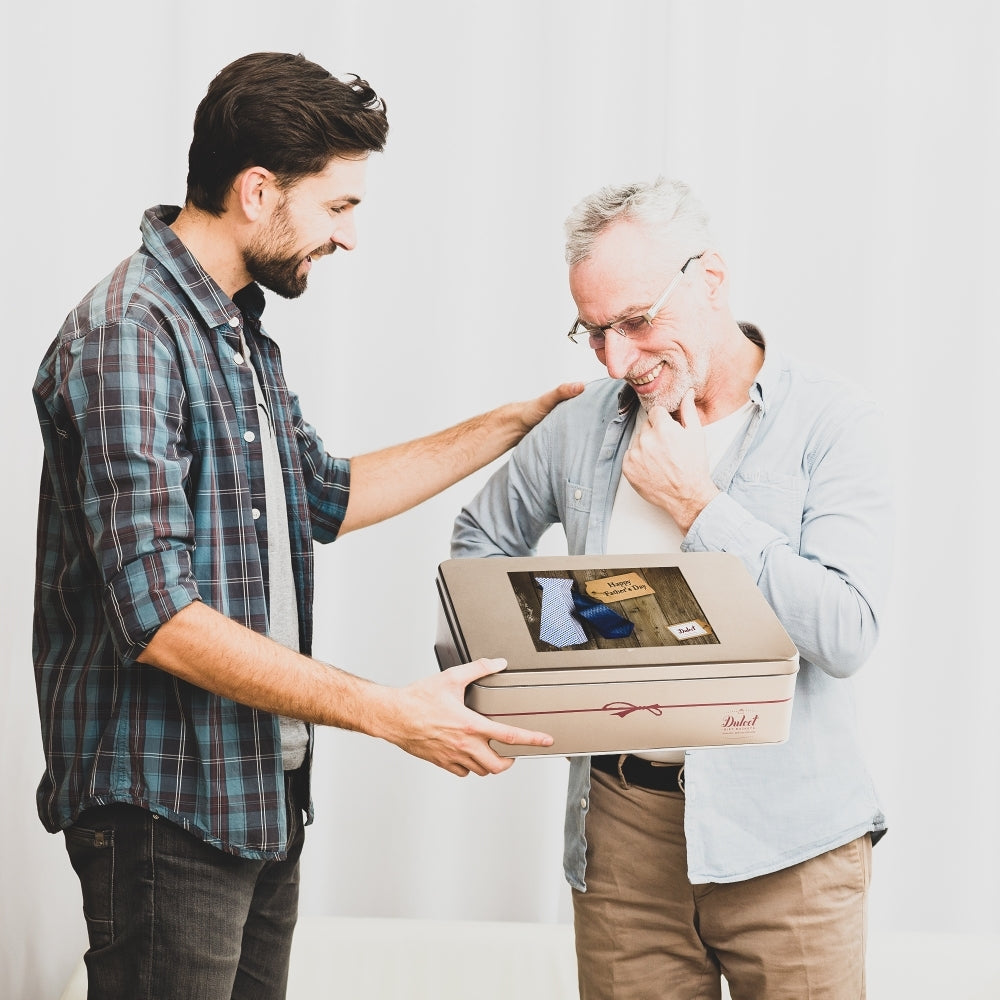 Gift tin being handed between two men, one holding a greeting package